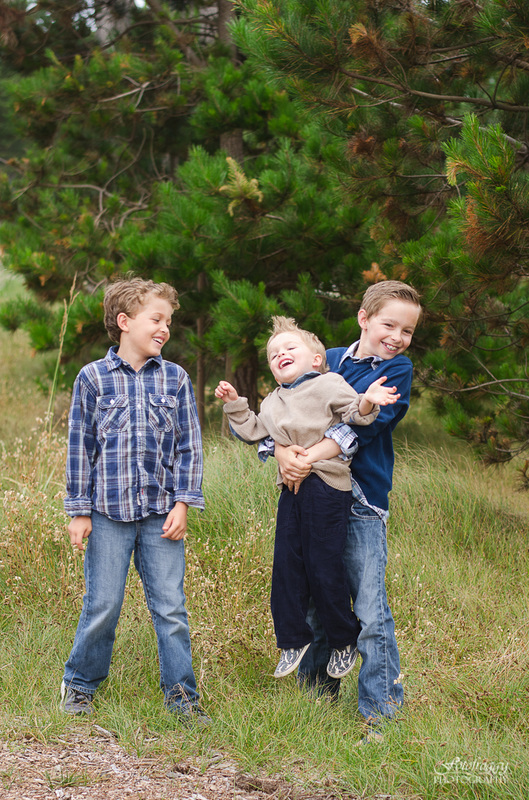 Three brothers playing in grass dark blue Pacific Grove portraits