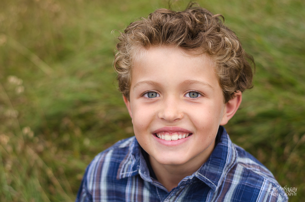 Closeup portrait of curly haired blue eyed boy in plaid shirt