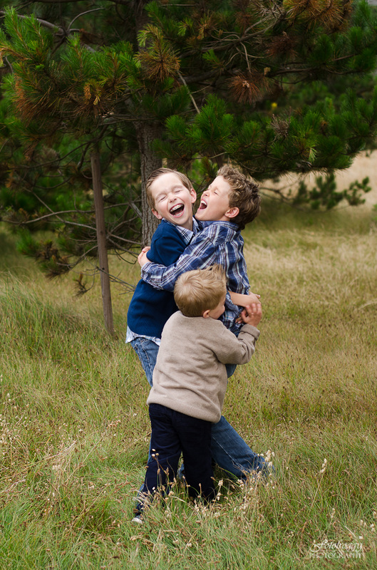 Two brothers hugging joined by younger brother in Pacific Grove portraits
