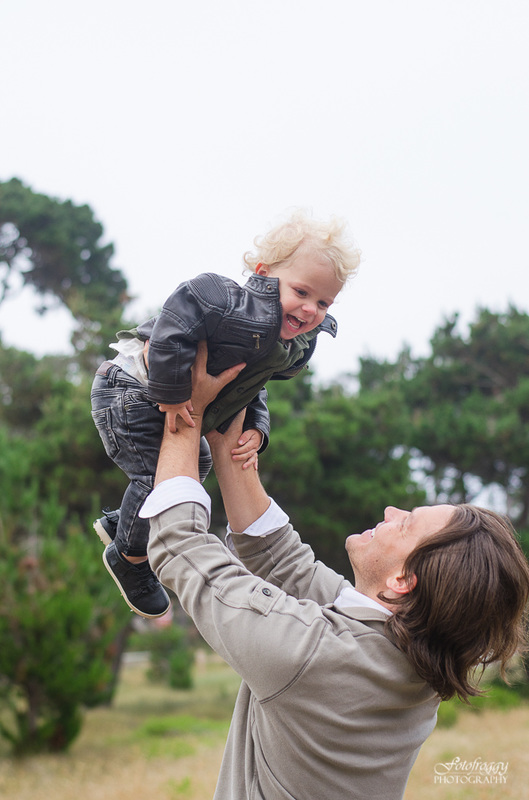Father lifting baby boy in the air with black leather jacket