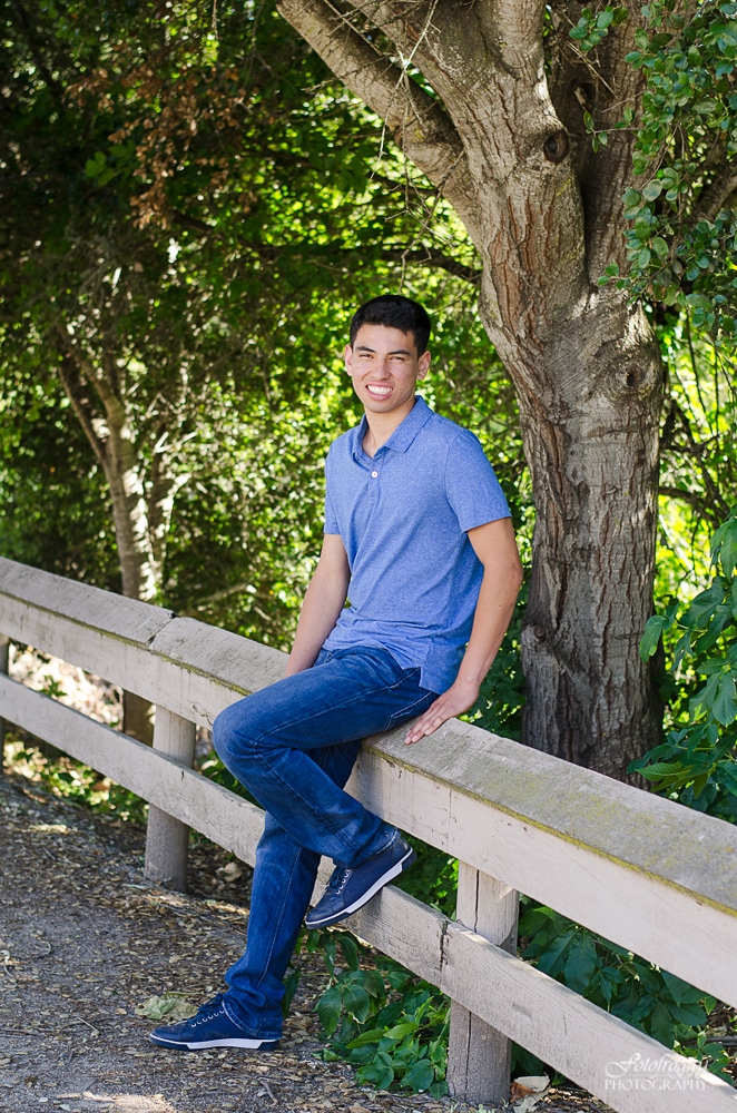 Senior boy posing on fench railing.