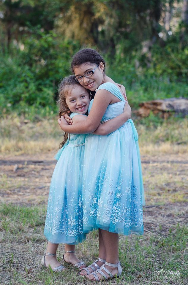 Sister hugging in matching blue dresses. Pacific Grove family portraits. www.fotofroggy.com